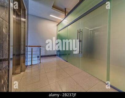 Modern frosted glass doors entrance near elevator in corporate office building Stock Photo