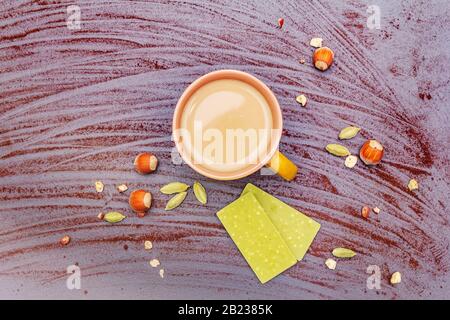 Coffee cup, chocolate with matcha tea, hazelnuts, cocoa powder and cardamon. Hot sweet drink concept. Stone concrete background, top view, close up Stock Photo