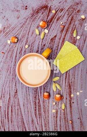 Coffee cup, chocolate with matcha tea, hazelnuts, cocoa powder and cardamon. Hot sweet drink concept. Stone concrete background, top view, close up Stock Photo