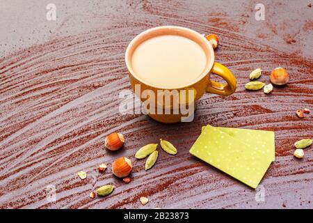 Coffee cup, chocolate with matcha tea, hazelnuts, cocoa powder and cardamon. Hot sweet drink concept. Stone concrete background, close up Stock Photo