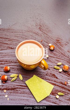 Coffee cup, chocolate with matcha tea, hazelnuts, cocoa powder and cardamon. Hot sweet drink concept. Stone concrete background, close up Stock Photo