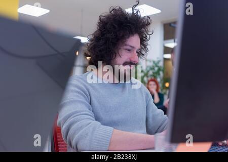 Young male web developer working and brainstorming about business plan on meeting at sunny bright office interior. Stock Photo