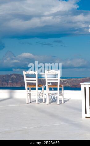 Postkartenidylle - Zwei weisse Stuehle mit Blick auf Santorin Stock Photo