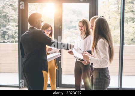 Six young business people analyze the results and discuss them. Group of business people collaborating on project in office Stock Photo