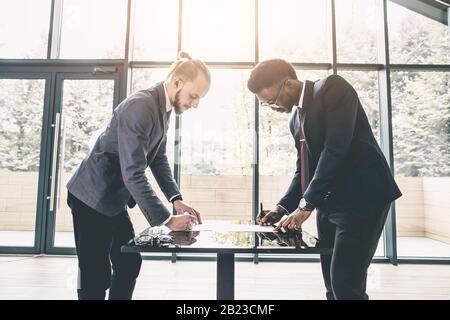 Young Caucasian businessman shaking hands to seal a deal with his partner pretty woman. Multiethnical group of business people having a business Stock Photo