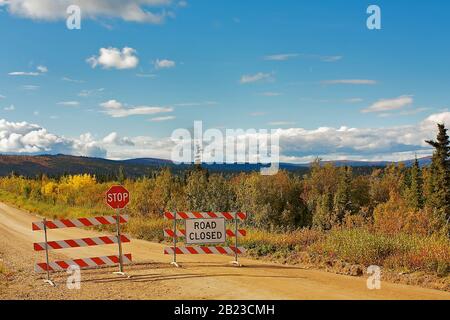 Top of the world highway, Alaska, USA: Road works / construction site with road closed sign, stop sign and barrier on dirt road Stock Photo