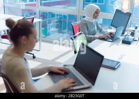 Two multiethnic Young female business women using laptopat her work and staying alone after work to finish her job. Stock Photo