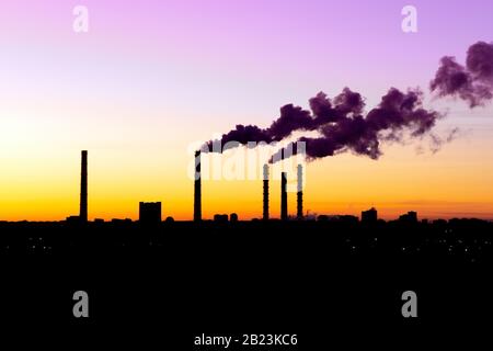 Bad air quality. Air pollution from factory. Smoke from chimney of industrial pipe on sunset sky. Global warming problem concept.