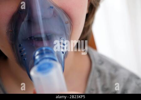 girl suffering from cough using a nebulizer to cure her condition Stock Photo