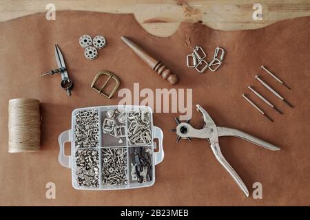 Creative background consisting of handtools, container with supplies, threads and other stuff on piece of brown suede Stock Photo