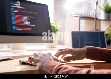Hands of young contemporary programmer over keypad during work over new software in front of computer screen in office Stock Photo