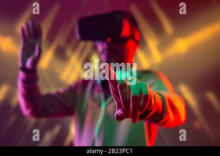 Forefinger of young man with vr headset pressing virtual button or touching display while traveling in augmented reality Stock Photo
