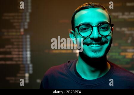 Happy young man with toothy smile standing in front of camera against large screen with decoded information Stock Photo