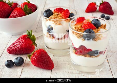 Strawberry and blueberry parfaits in glasses against a bright white wood background Stock Photo