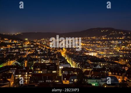 Germany, Aerial view above illuminated skyline of city stuttgart houses in basin in cold winter night with starry sky Stock Photo