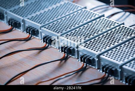 Metal mesh cases of power supply and wires are on a wooden table at the production of high-tech computers. Concept of high technology and industrial p Stock Photo