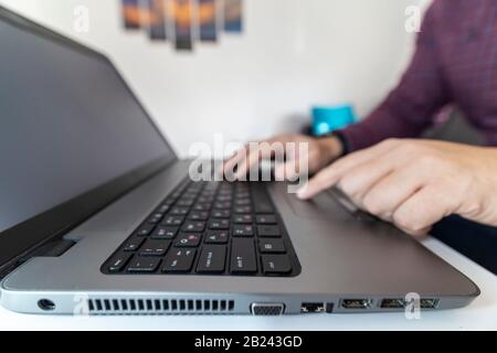 Low angle view macro shot of a man typing on a laptop keybord with blank screen. Stock Photo