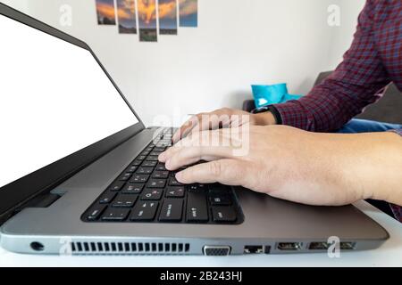 Low angle view macro shot of a man typing on a laptop keybord with blank screen. Stock Photo