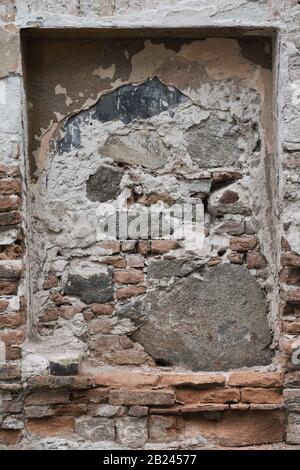 Abstract detail of weathered brick wall with cracked plaster and exposed old masonry Stock Photo