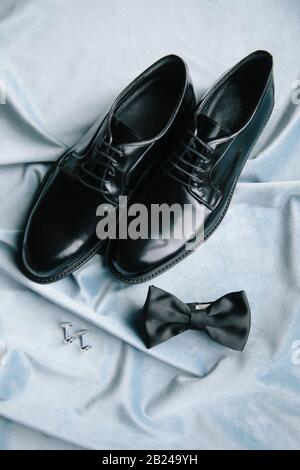 Groom accessories. Shoes, bow tie, and cufflinks. On the blue background. Stock Photo