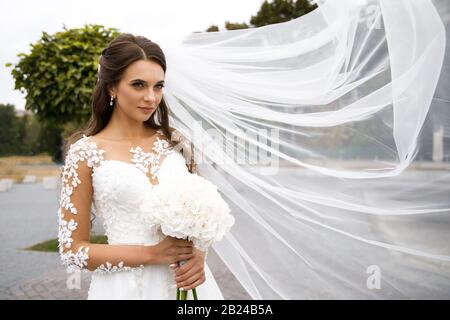Beautiful bride with a wedding bouquet in their hands outdoors in a park Stock Photo