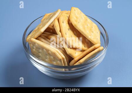 Square crackers in bowl on blue table Stock Photo
