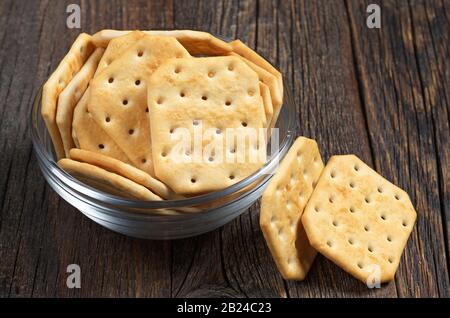 Square crackers in glass bowl on dark wooden background Stock Photo