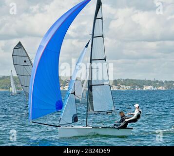 Children sailing / racing small sailboat with a blue spinnaker on a coastal lake. Teamwork by junior sailors racing on saltwater Lake Macquarie. Photo Stock Photo
