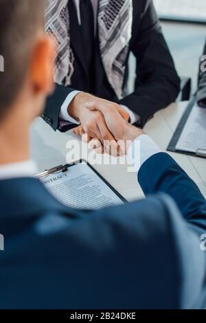cropped view of multiethnic businessmen shaking hands on meeting Stock Photo
