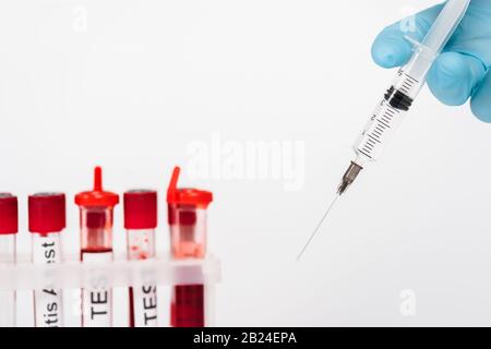 cropped view of scientist holding syringe near test tubes isolated on white Stock Photo