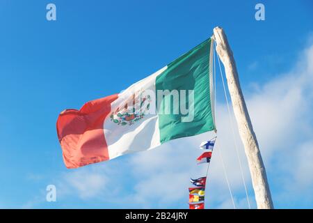 Mexican flag in the wind with small European flags on blue sunny sky Stock Photo