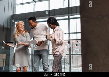 young african american businesswoman using digital tablet near multicultural colleagues holding papers Stock Photo