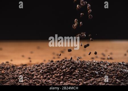 roasted coffee beans falling on pile on black background Stock Photo