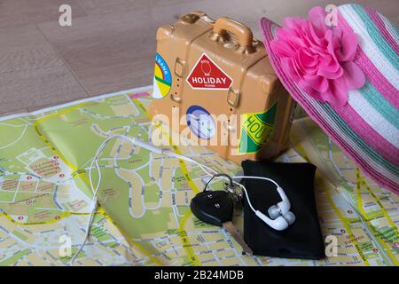 The map, car key, pink hat, earphones for phone are necessary for a summer travel to Spain. Set of travel things on wooden background. Travel concept. Stock Photo
