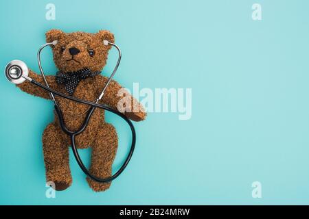 Top view of brown teddy bear with stethoscope on blue background, international childhood cancer day concept Stock Photo