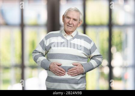 Senior caucasian man suffers from stomachache. Stock Photo