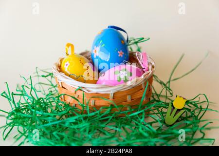 Easter color eggs in nature wicker basket on pastel background. Yellow, pink, blue. Easter concept. Stock Photo