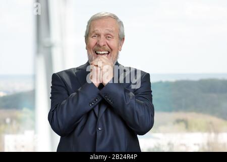 Senior businessman with folded hands rejoicing. Stock Photo