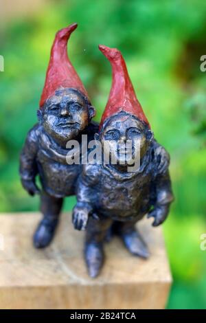 Beervelde, Belgium - October 13 2019: A top down portrait of two gnome statues made from metal. The steel gnomes are standing on a piece of wood and t Stock Photo