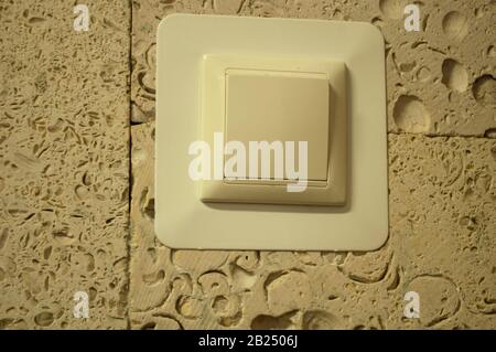 white square switch on the wall with a pattern of seashells Stock Photo