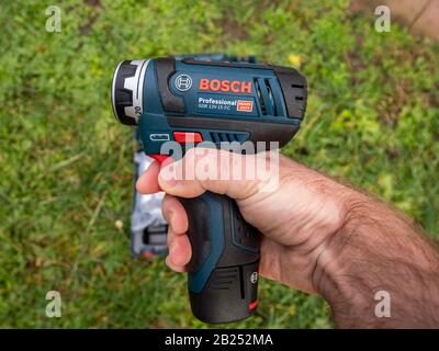 Paris, France - Feb 18, 2020: Man hand testing holding in hand POV personal persoective of a new Bosch Professional GSR 12 V-15 FC cordless drill driver set heavy duty Stock Photo