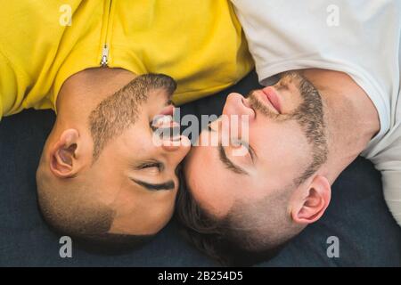 Portrait of a happy gay couple spending time and laying down on the floor. Lgbt and love concept. Stock Photo