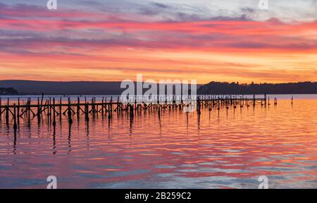 Deep colours of orange and red in the skies over a Poole Harbour jetty near Sandbanks Stock Photo