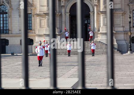 LIMA / PERU - May 10 2016: Guards in red and white uniforms, metal hats, and ceremonial swords and flags standing at attention in front of the Preside Stock Photo