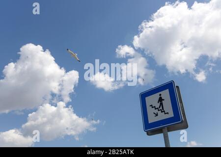 Stair sign close-up on the background of cloudy sky and seagull flying in the air. Stock Photo