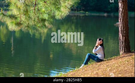 Young people are happily listening to music in their headphones in the midst of nature and the warm light of the morning. Stock Photo