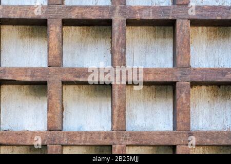 Old wooden cells on a white wall. Vintage brown background. Stock Photo