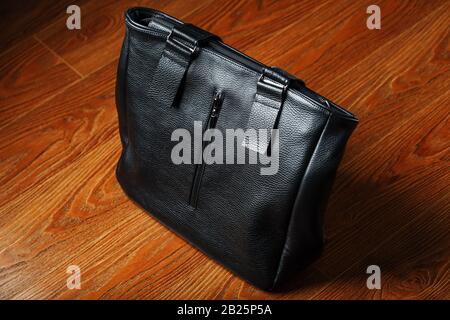 Handmade black leather bag on a wooden background, made of natural material. Design, Hobbies and businesses. Stock Photo