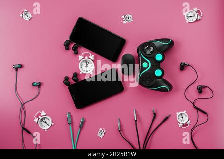 A toothy Smart Fish from gadgets devours time on a pink background. The creature in the form of various gadgets for smartphones, gamepad and headphone Stock Photo