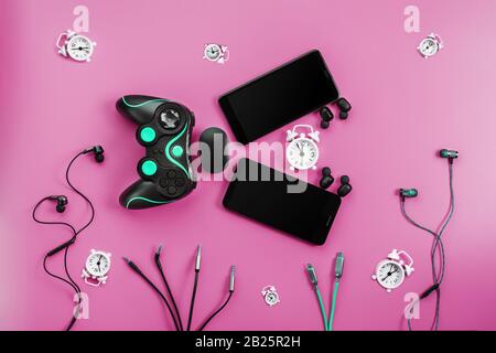 A toothy Smart Fish from gadgets devours time on a pink background. The creature in the form of various gadgets for smartphones, gamepad and headphone Stock Photo